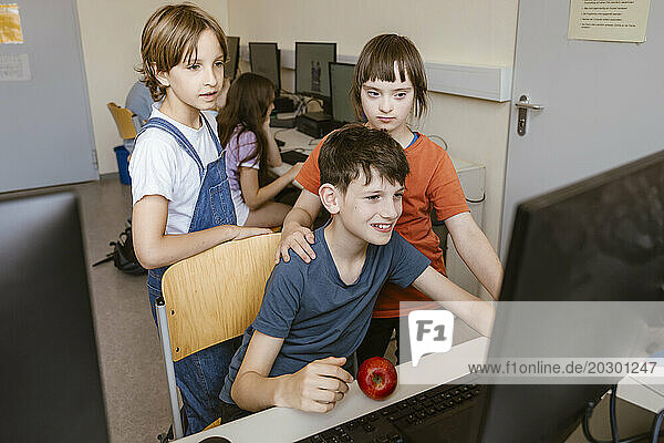 Male and female students with down syndrome girl using computer at desk in classroom
