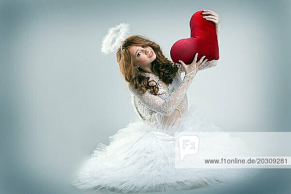 Hübsches Mädchen als Engel gekleidet posiert mit Teddy Herz