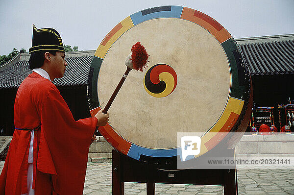 South Korea. Jongmyo Royal Confucian Shrine. Man striking a ceremonial gong.