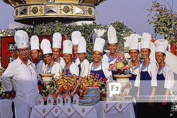 Vietnam. Ho Chi Minh city. Rex Hotel chefs posing outdoors with food display.