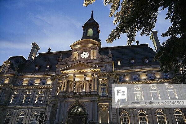Second empire style multistory Montreal City Hall building facade with lights on at dusk  Old Montreal  Quebec  Canada  North America