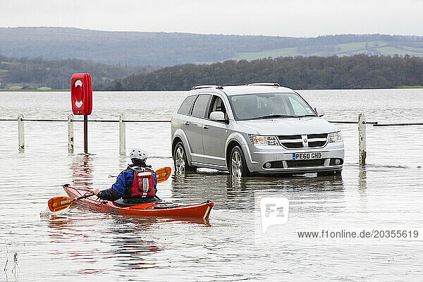 Kayaker and car in flooded street in Storth at Kent river estuary