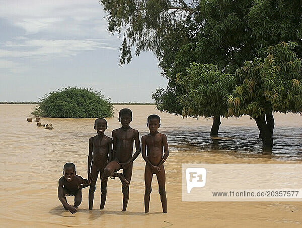 Four naked African Songhai children standing on the edge of a large dirty lake  Gossi  Mali  West Africa