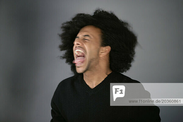 African American man with huge afro shakes head and screams.