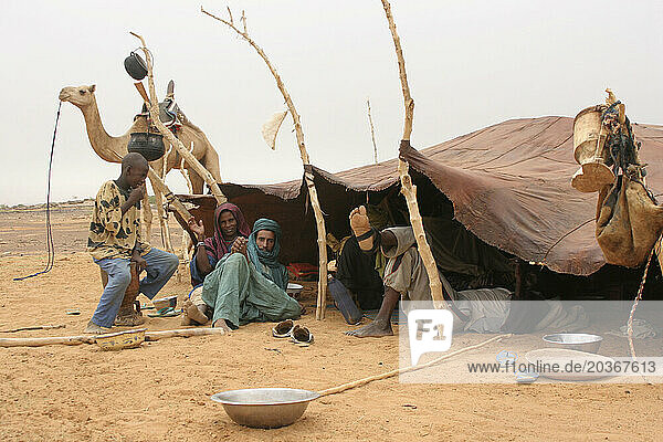 An African Islamic Toureg man ties up his camel and stops to rest at a nomadic encampment in the Sahel  Mali  West Africa
