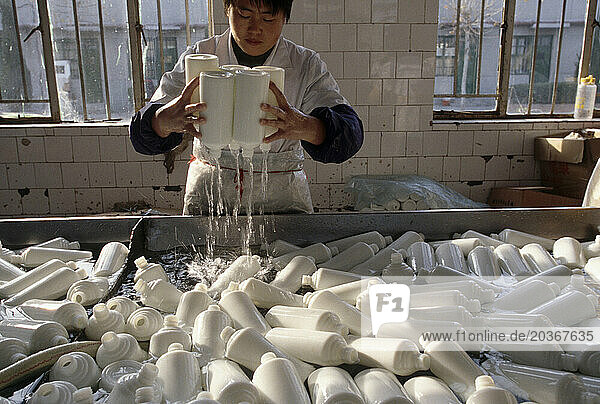 A female factory worker washing bottles at a liquor company  China