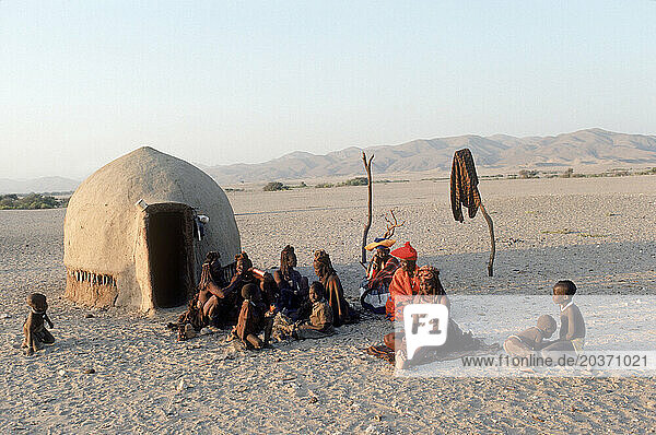 Himba people sitting outside a hut in their village  Namibia.