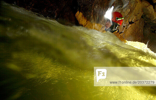 A cave explorer negotiates some deep water in a cave in England