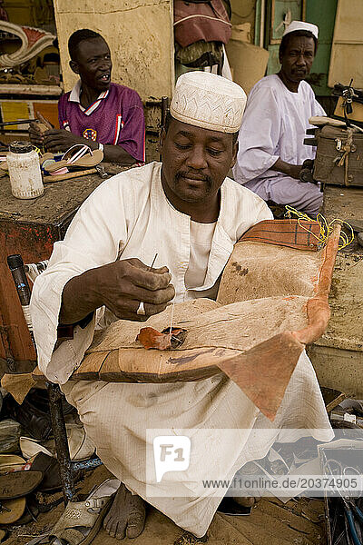 Leather repair shop at a market in El Obeid  North Kordofan  Sudan. He is repairing a camel saddle.