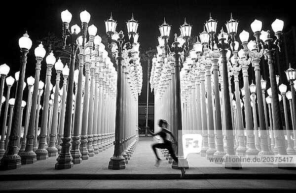 An athletic woman runs past rows of lights in Los Angeles  California.
