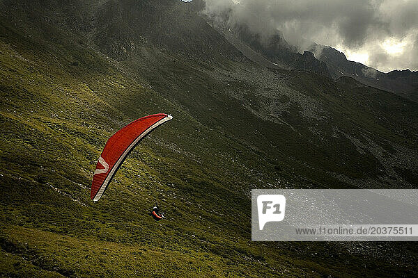 A paraglider soaring on a cloudy day near Roseland Pass in Savoie  France.