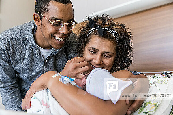 Multiracial couple smiles at brand new baby right after giving birth