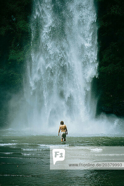 Man traveler  in the jungle  goes to the Nungnung waterfall. Bali