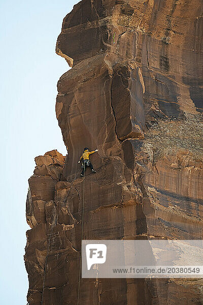 Low angle view of man rock climbing on cliff at desert