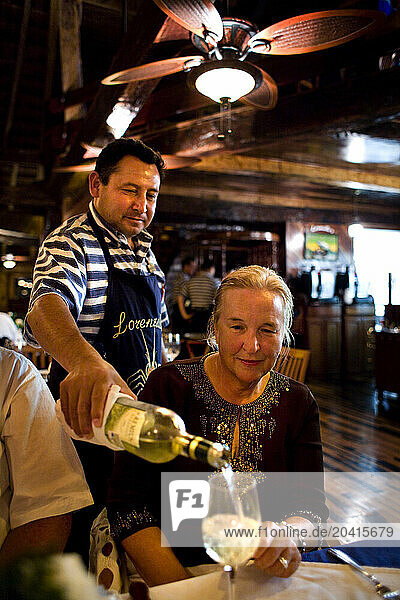 A waiter pours white wine for a guest at a restaurant in Cancun, Mexico.