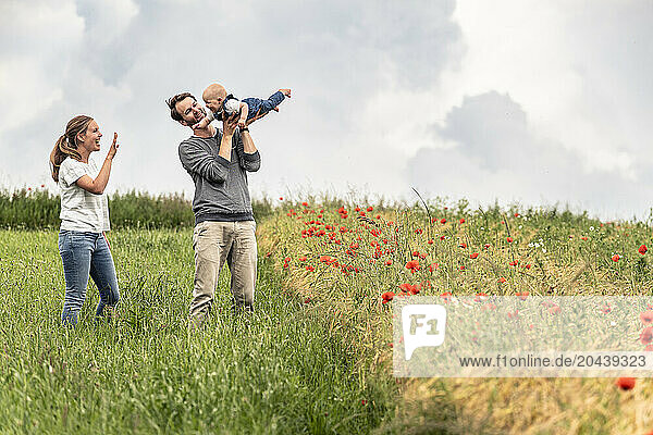 Happy family playing with daughter in meadow