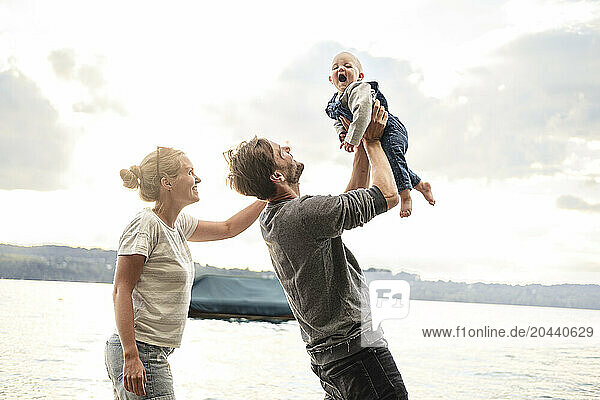 Happy father holding daughter in arms under clear sky