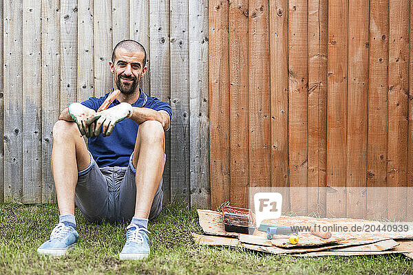 Smiling man sitting with paintbrush in back yard