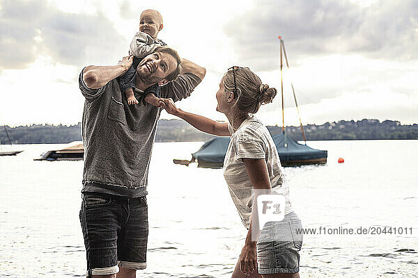 Happy family playing with daughter at lake