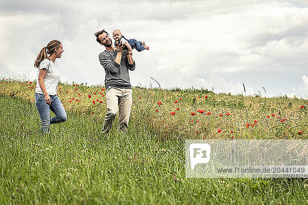 Father holding daughter in mid air and playing in meadow