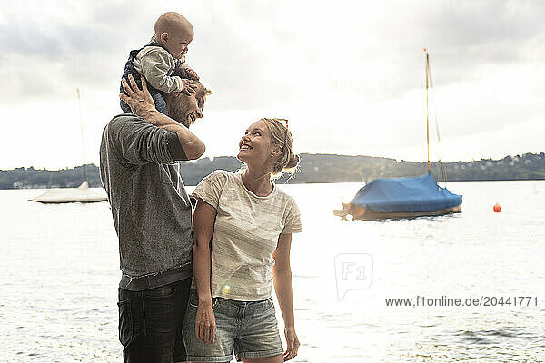Cheerful family enjoying with daughter at lake