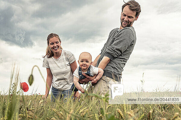 Family enjoying together in meadow under blue sky