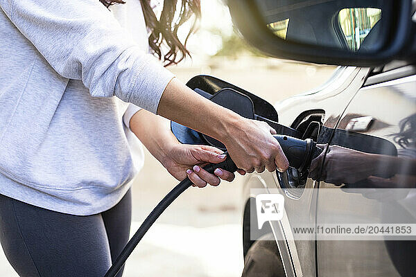 Woman charging electric car at station