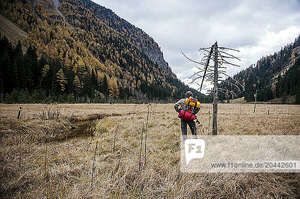 Senior man with backpack standing in front of mountains