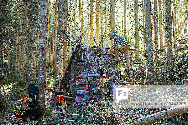 Senior man building shelter in forest