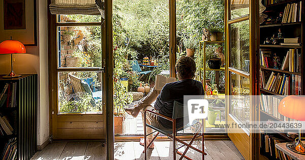 Man reading book in living room and sitting near doors
