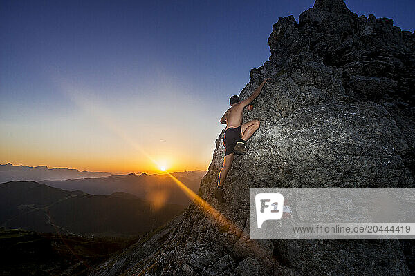 Young hiker climbing Steinfeldspitze rock at sunrise in Altenmarkt  Zauchensee  Salzburg  Austria
