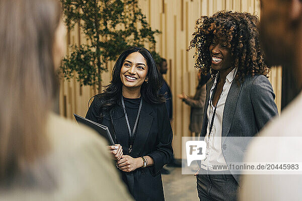 Happy female entrepreneurs talking with delegates during networking event at convention center