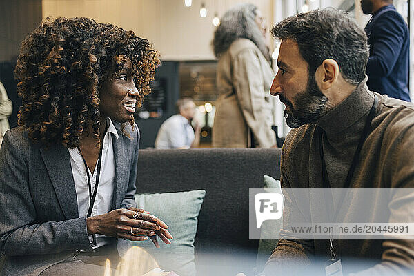 Smiling female business professional discussing with male entrepreneur during networking event at convention center