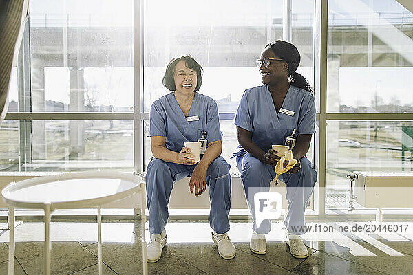 Happy female medical professionals enjoying during coffee break in hospital