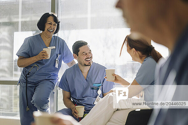 Happy team of male and female doctors enjoying during coffee break at hospital