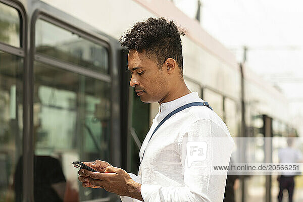 Man using smart phone and waiting for bus at street