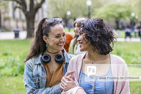 Happy women talking and walking with arm in arm at park
