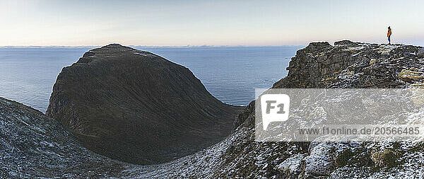 Hiker standing on mountain of Lofoten island in Norway