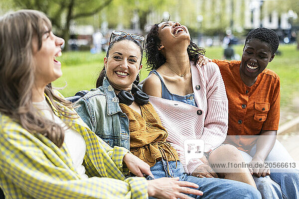 Cheerful multiracial female friends sitting together and laughing