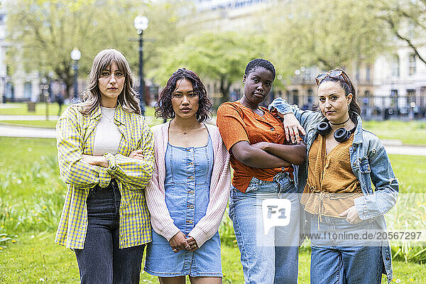 Confident female friends standing side by side at park