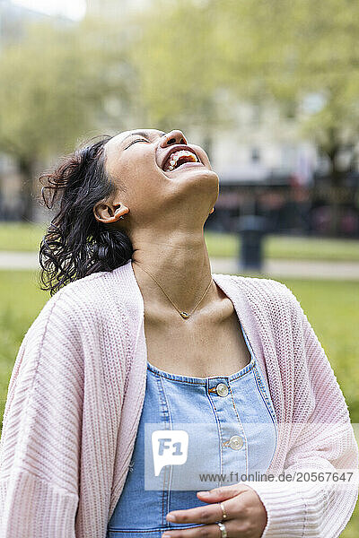 Cheerful woman laughing with head back at park