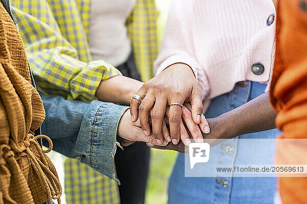 Multiracial women stacking hands together