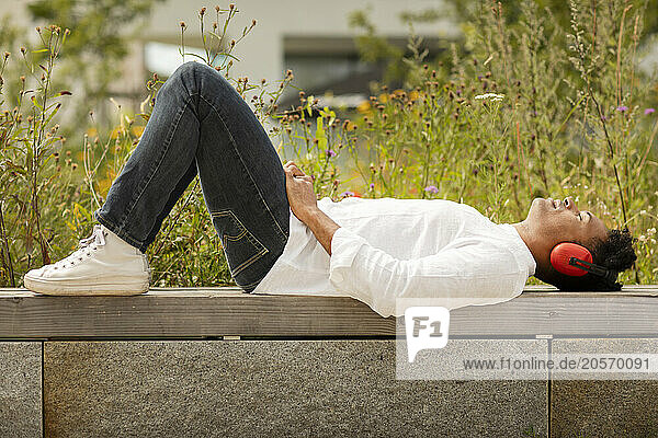 Man with wireless headphones lying down on bench