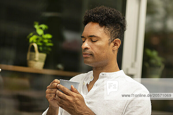 Man with eyes closed holding coffee cup