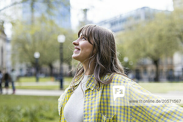 Smiling beautiful young woman wearing checked pattern shirt looking away at park