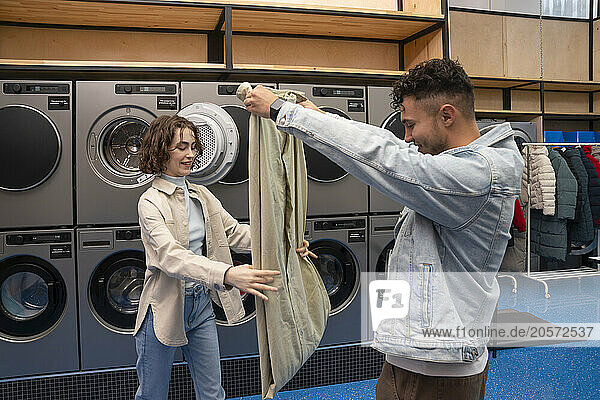 Young couple folding sheet together at laundromat