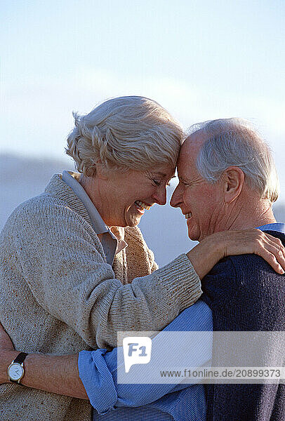 Senior man & woman couple outdoors close up in affectionate embrace.