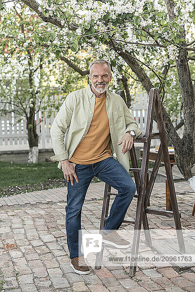 Smiling man standing by ladder in back yard