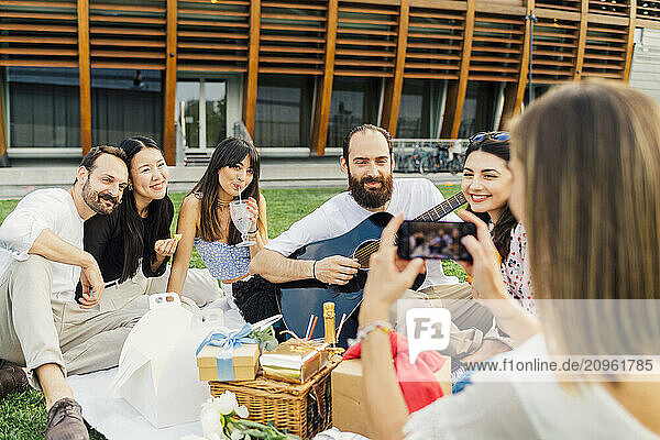 Woman photographing friends with smart phone in park