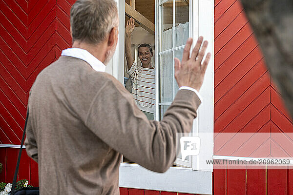 Happy woman waving at man leaving for work